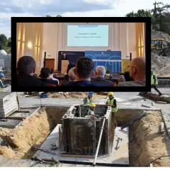Budowa postępuje powoli, jakby dotknięta skutkami nadmiernego planowania w Excelu (worldbuilder's disease). Na placu budowy widać robotników, a w tle ekran z prezentacją.