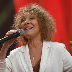 Uśmiechnięta Alicja Majewska z mikrofonem, w białej marynarce. Ile lat ma Majewska Alicja? To pytanie zadaje sobie wielu fanów.