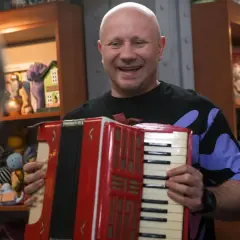 Mariusz z lombardu, grając na akordeonie, wygląda na szczęśliwego. Nie wiadomo, ile lat ma Mariusz z lombardu.