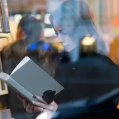 Kobieta czyta książkę w księgarni. Autorzy mogą poznać jakie dane o sprzedaży książek są dostępne dla nich dzięki Nielsen Bookscan.