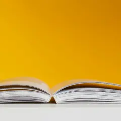 Otwarta książka na białym tle, symbolizująca kolejne etapy procesu wydawniczego od akceptacji do premiery.