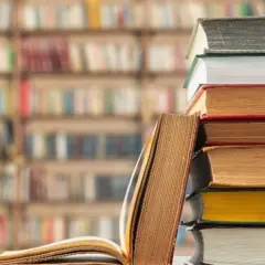 Stos książek na tle biblioteki. Unikaj chaosu w nazewnictwie zakładek w dużym projekcie literackim, by nie zgubić wątku.