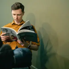 Młody mężczyzna czyta książkę, zastanawiając się, jakie książki z nurtu cli-fi warto przeczytać w 2026.
