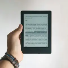 Dłoń trzyma czytnik e-booków. Tekst na ekranie dotyczy zasad ochrony praw autorskich przy wydawaniu e-booków.