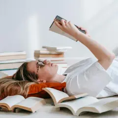 Dziewczyna leży wśród książek, zastanawiając się nad różnicą między retellingiem baśni a klasyczną adaptacją literacką.