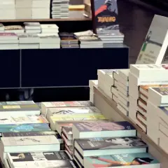 Książki na półkach i stołach w księgarni stacjonarnej. Różnica między sprzedażą w księgarniach stacjonarnych a dystrybucją online jest widoczna w sposobie prezentacji.