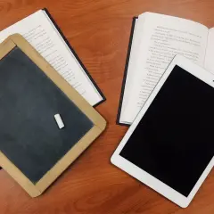Tablica, książka i tablet na drewnianym stole. Czy postać literacka może istnieć bez konfliktu wewnętrznego?