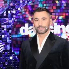 Maserak, ile lat ma? Uśmiechnięty mężczyzna w czarnym smokingu na tle błyszczącej sceny "Dancing with the Stars".