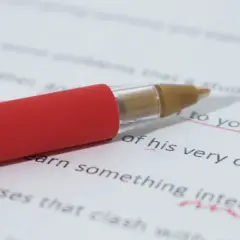 Czerwony długopis na białej kartce z tekstem. Podkreślone fragmenty tekstu sugerują korektę, być może dotyczącą tego, jakie są najczęstsze błędy w tworzeniu sztucznych języków (conlangs).