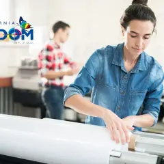 Kobieta w drukarni przygotowuje materiał do druku. To pokazuje, jak różnica między wydaniem papierowym a wersją "print on demand" jest realizowana w praktyce.