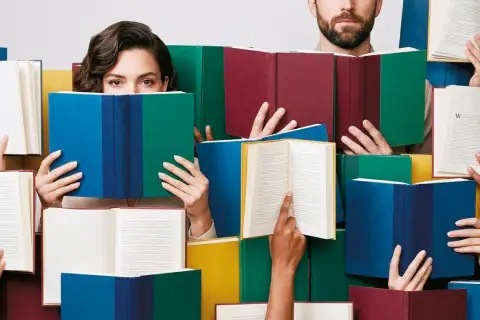 Ludzie czytają książki, odzwierciedlając jakie są trendy w literaturze faktu i reportażu wydawniczym 2026.
