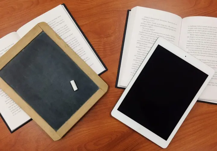 Tablica, książka i tablet na drewnianym stole. Czy postać literacka może istnieć bez konfliktu wewnętrznego?