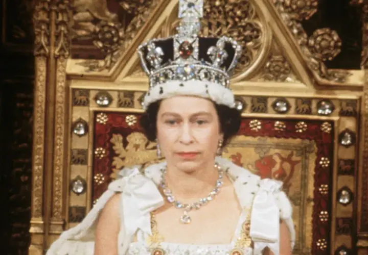 Królowa Elżbieta II w koronie i szacie, siedząca na tronie. Zastanawiamy się, ile żyła królowa Elżbieta, która panowała przez dekady.