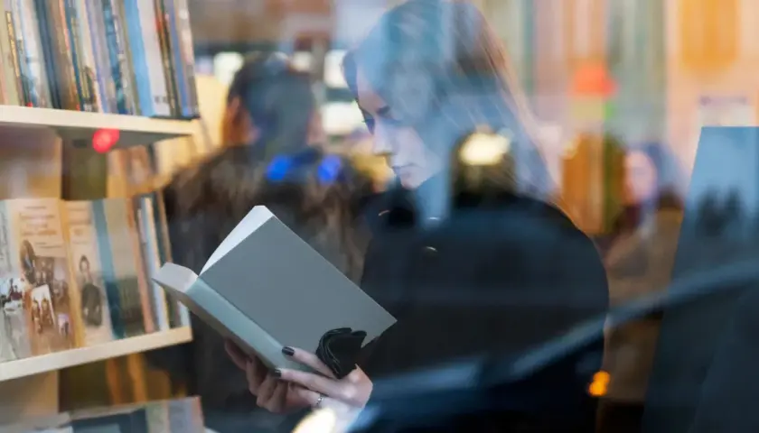 Kobieta czyta książkę w księgarni. Autorzy mogą poznać jakie dane o sprzedaży książek są dostępne dla nich dzięki Nielsen Bookscan.