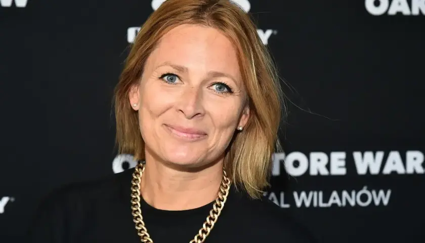 Kobieta z blond włosami i złotym łańcuchem na szyi. Ile lat ma odeta moro? Trudno powiedzieć, ale wygląda na około 40 lat.
