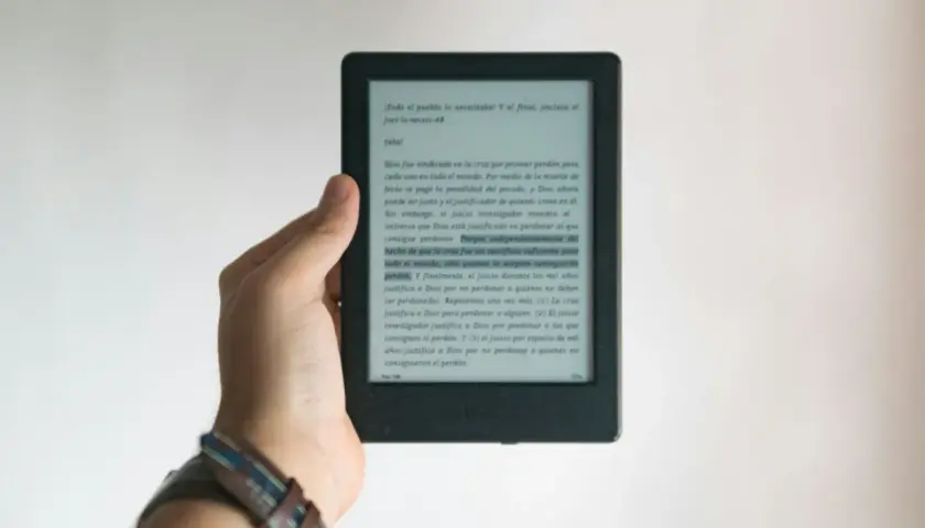Dłoń trzyma czytnik e-booków. Tekst na ekranie dotyczy zasad ochrony praw autorskich przy wydawaniu e-booków.