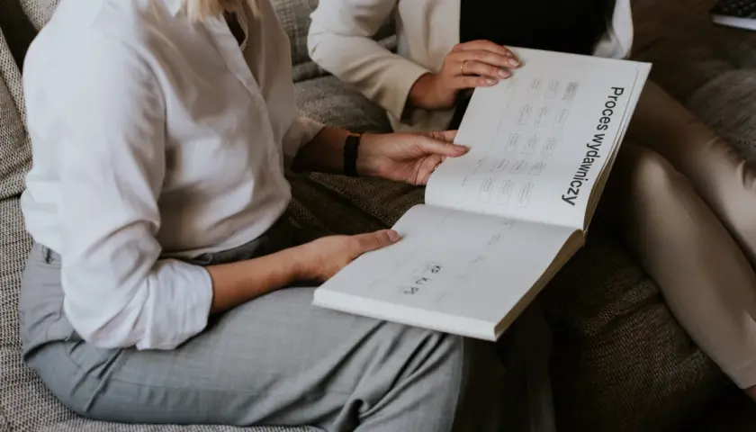 Dwie kobiety analizują schemat "Proces wydawniczy". Zły skład typograficzny książki może utrudniać zrozumienie, jak ten proces przebiega.