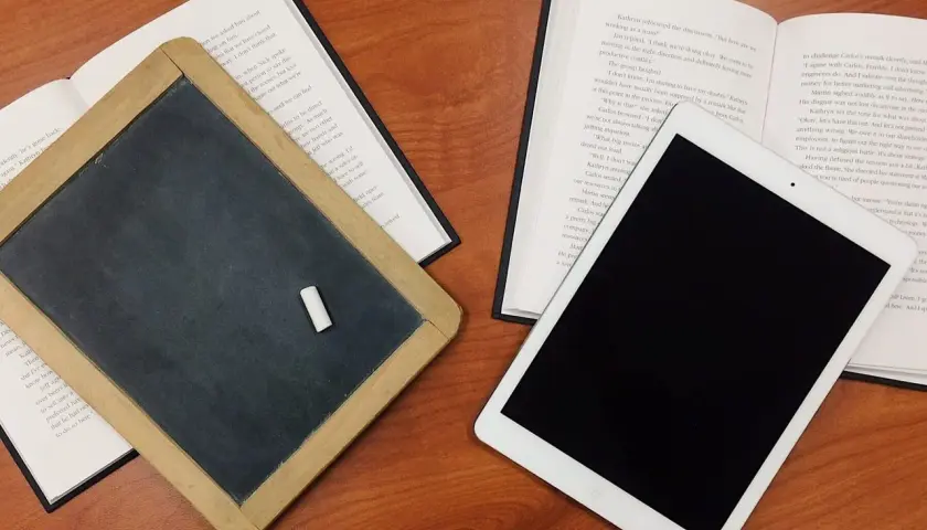 Tablica, książka i tablet na drewnianym stole. Czy postać literacka może istnieć bez konfliktu wewnętrznego?