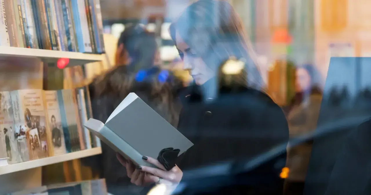 Kobieta czyta książkę w księgarni. Autorzy mogą poznać jakie dane o sprzedaży książek są dostępne dla nich dzięki Nielsen Bookscan.