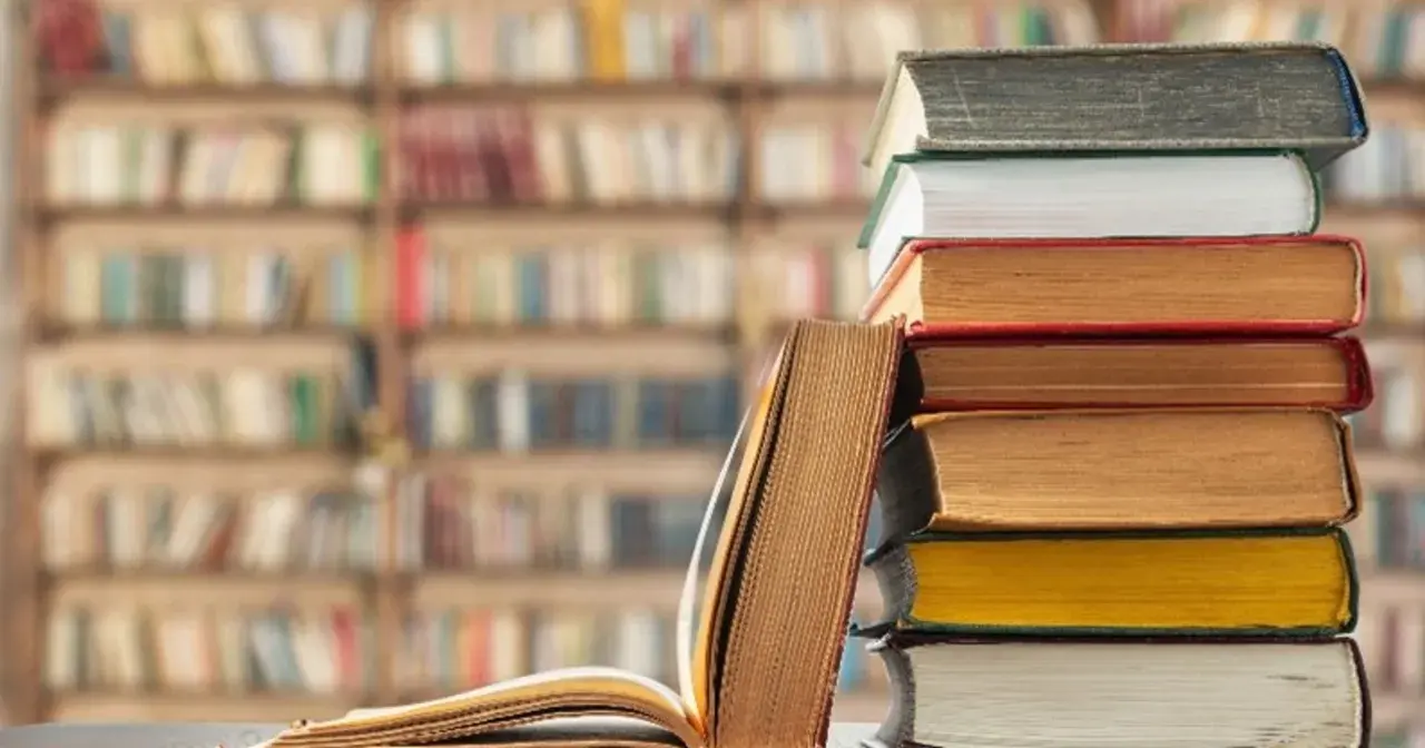 Stos książek na tle biblioteki. Unikaj chaosu w nazewnictwie zakładek w dużym projekcie literackim, by nie zgubić wątku.