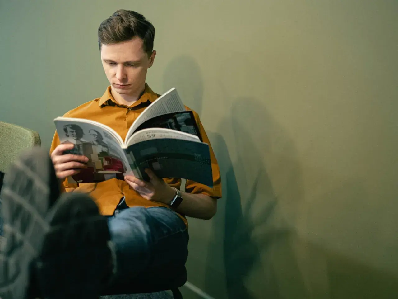 Młody mężczyzna czyta książkę, zastanawiając się, jakie książki z nurtu cli-fi warto przeczytać w 2026.