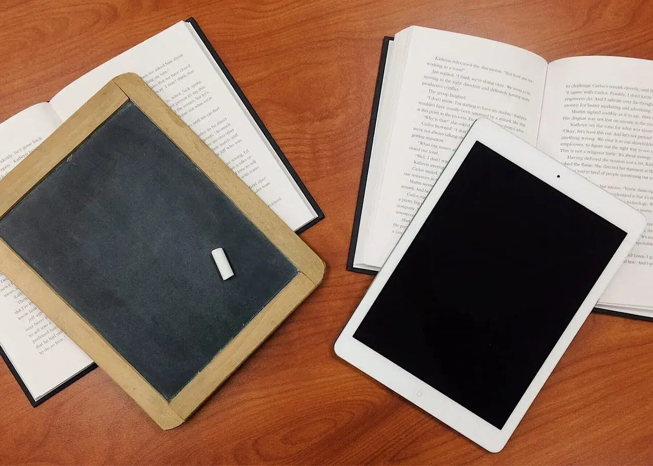 Tablica, książka i tablet na drewnianym stole. Czy postać literacka może istnieć bez konfliktu wewnętrznego?