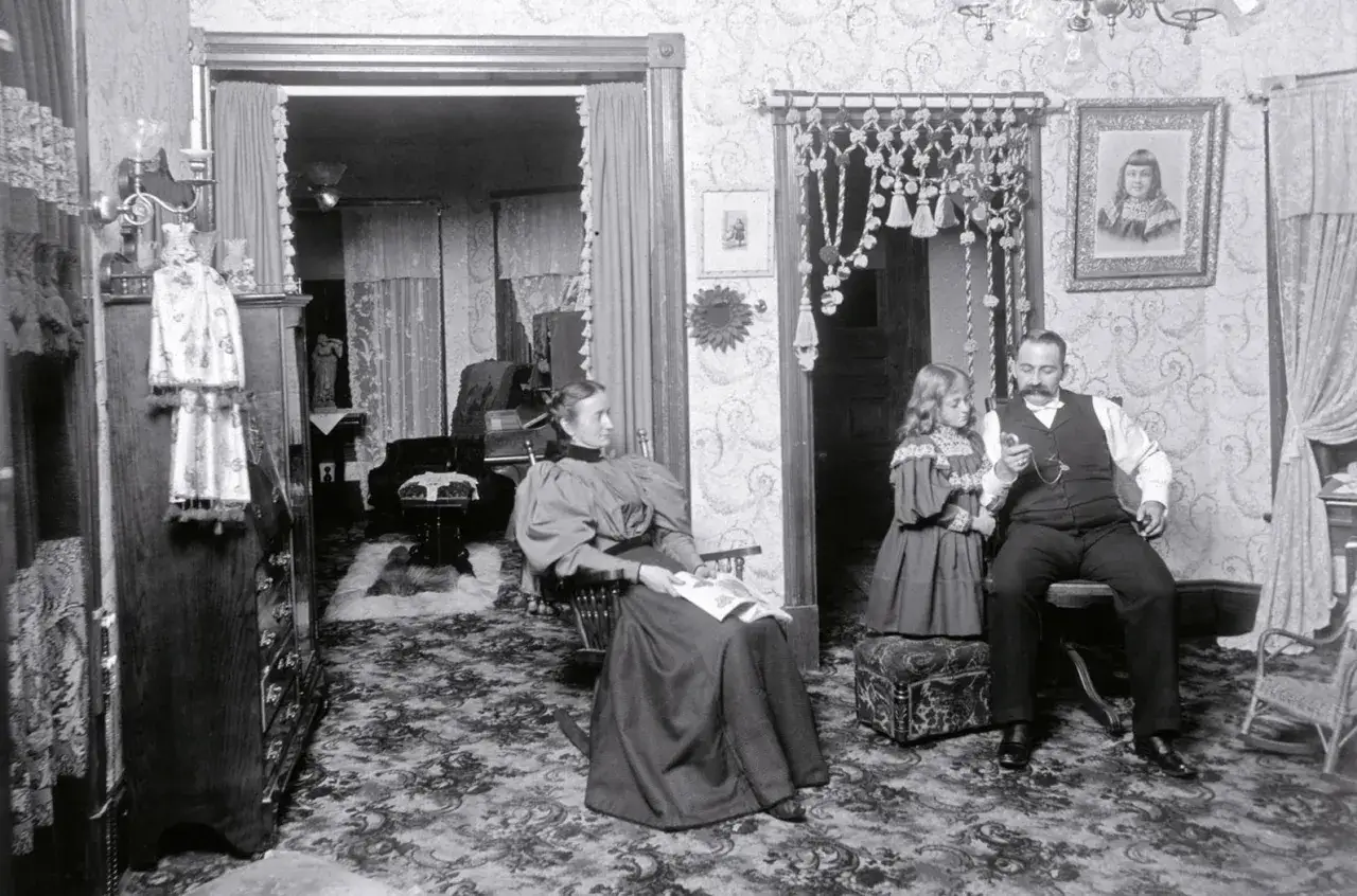 Rodzina w salonie, ojciec z córką, matka czytająca. Scena odzwierciedla objawy kryzysu małżeńskiego w literaturze realizmu mieszczańskiego.
