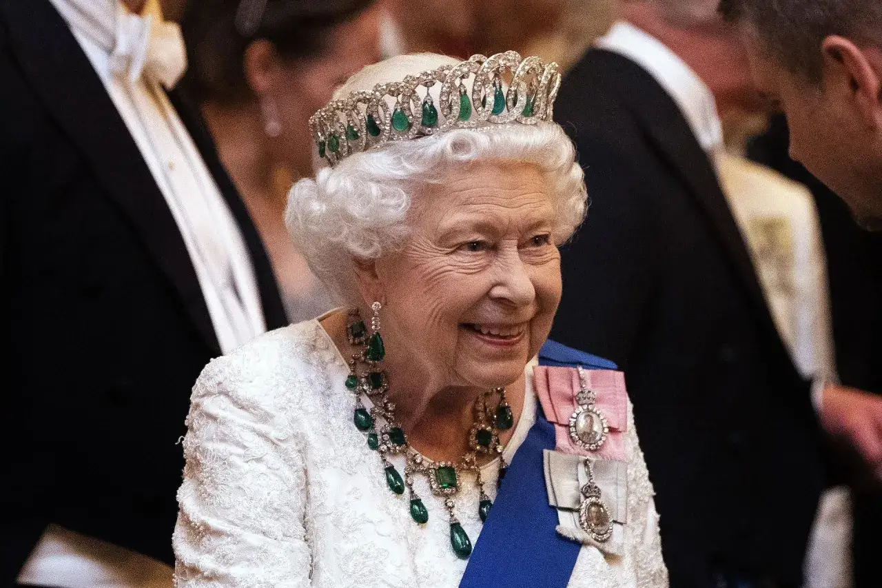 Królowa Elżbieta II w koronie i klejnotach, uśmiechnięta. Jej panowanie, trwające 70 lat, to najdłuższe w historii Wielkiej Brytanii.